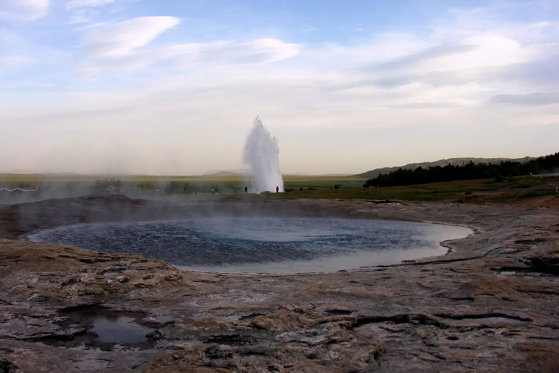 Great Geysir pool with an eruption of Strokkur behind it