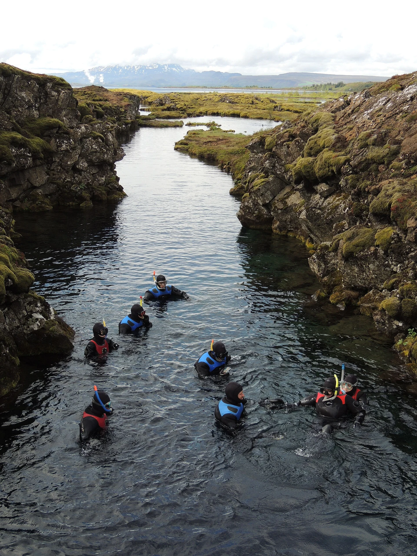 Snorkelers floating in Silfra between the rock walls