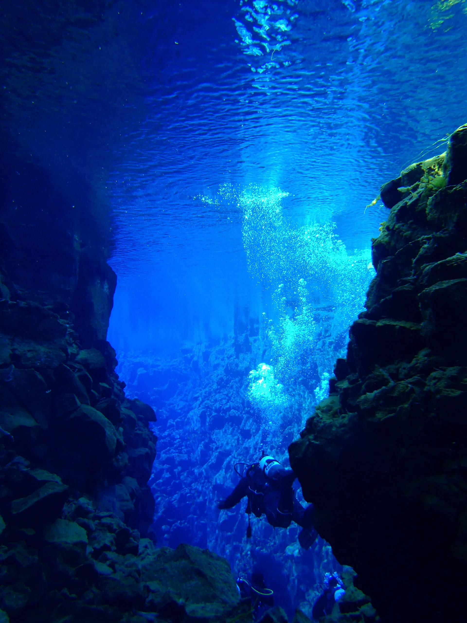 Scuba diver below the surface between Silfra rock walls